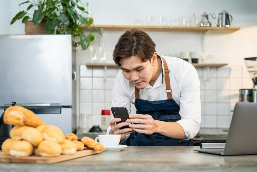 Asian businessman cafe owner take photo of cup of coffee for marketing.