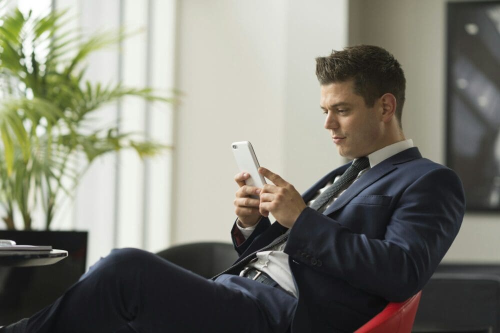 Businessman sitting in office looking at smartphone