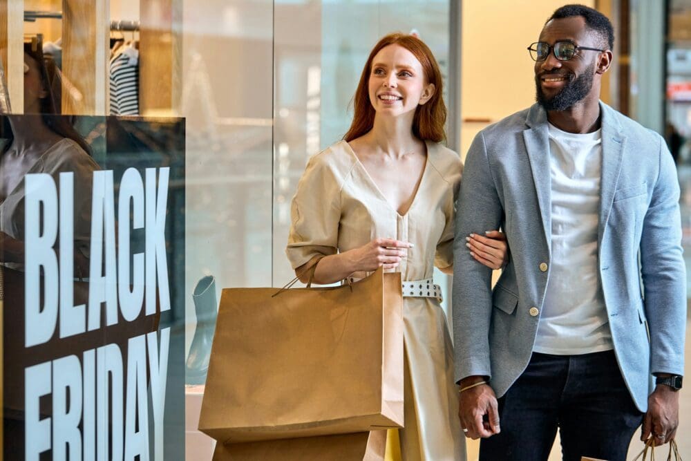 joyful diverse couple taking part in black friday global sale