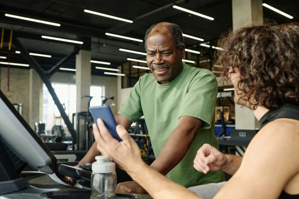 Senior Man Looking at Phone Screen at Gym