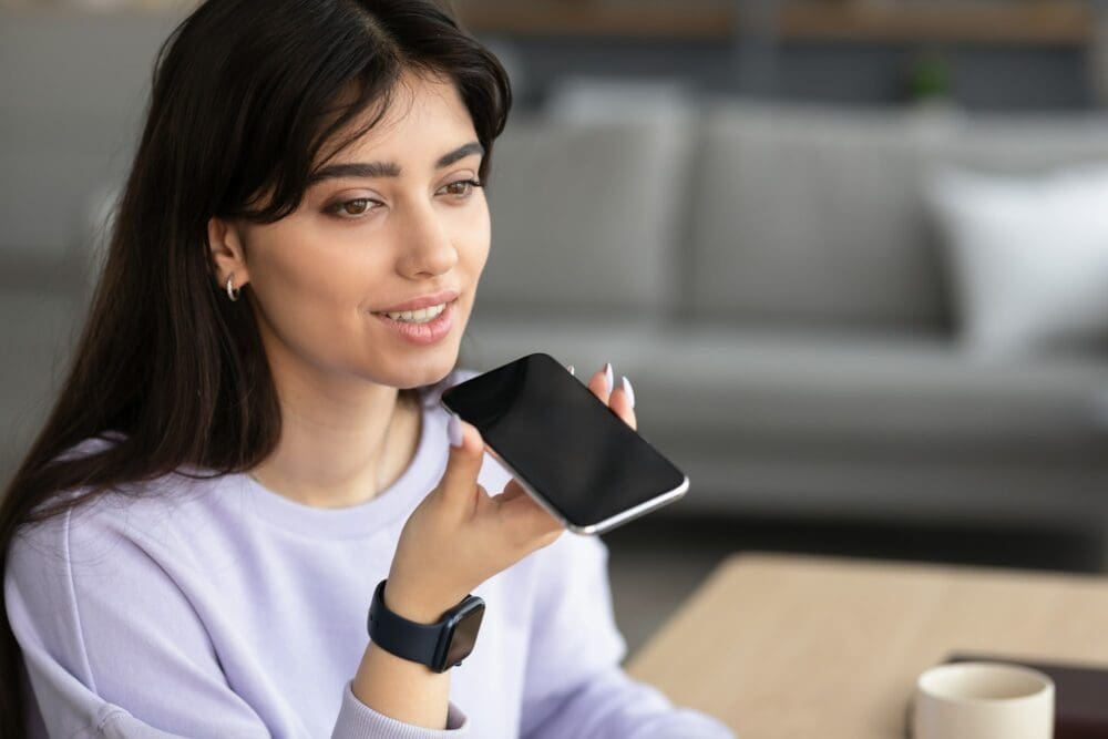 Smiling woman using voice search assistant on smartphone